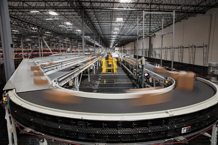 Boxes speed by on a conveyor belt in a warehouse with no humans around.